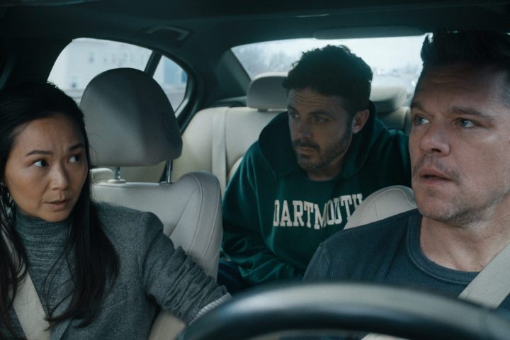 A man sits in the car with a woman beside him and another man in the back seat.