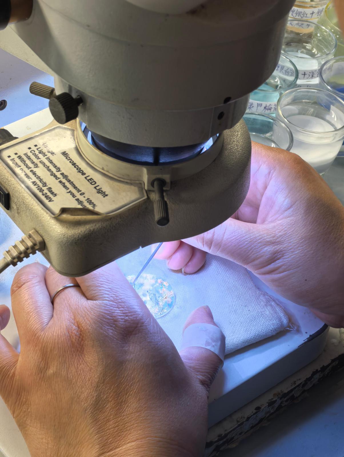 A microscope is used to meticulously apply the various enamel powders, each corresponding to a different colour, before the dial is fired